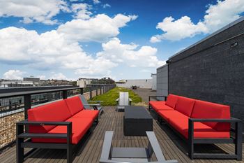 A roof deck with red couches and tables on a sunny day